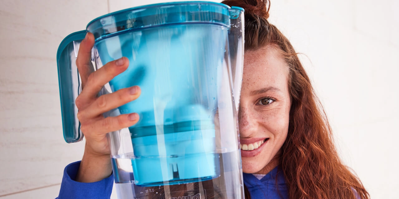Filter lime chlorine heavy metals Woman showing table water filter